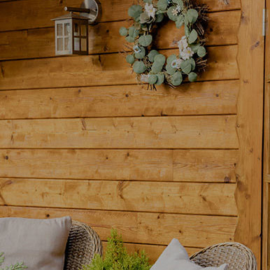 Wreath on a wooden wall with outdoor furniture and plants below